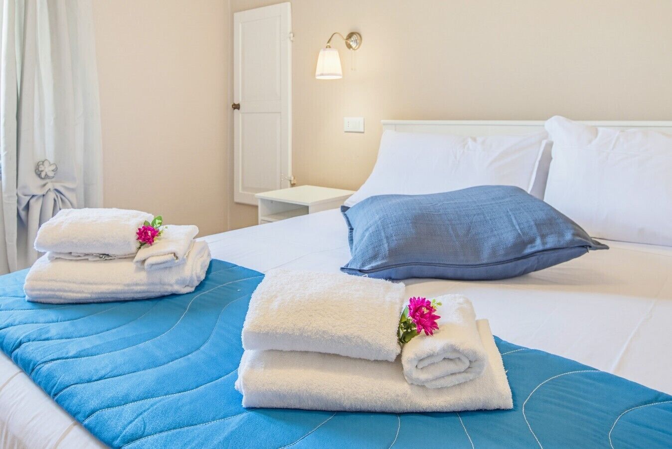 A hotel room with a bed, a nightstand, a mirror, and a window with curtains.