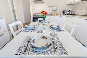 Ein Esstisch für vier Personen, gedeckt mit blumigem Tischlaufschütz und einer Blumenvase.
