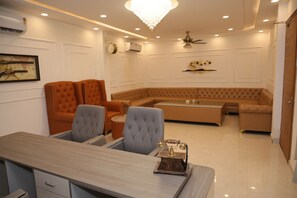 Uma sala de estar moderna com área de jantar, apresentando um lustre, um ventilador de teto e uma janela ampla.
