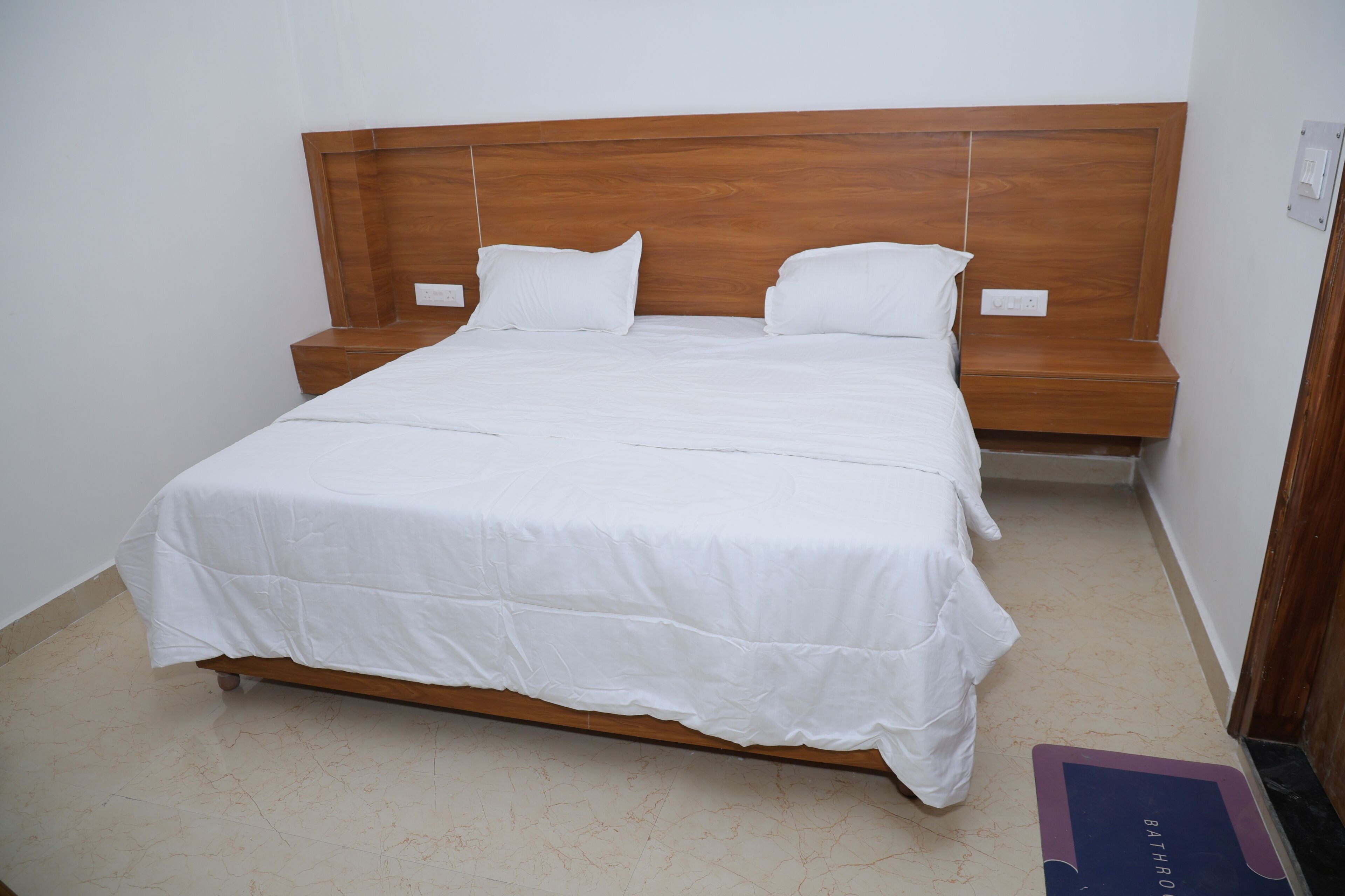 Ein Zimmer mit einem Einzelbett, einem Holzkopfstück, weißer Bettwäsche und einem Nachttisch.