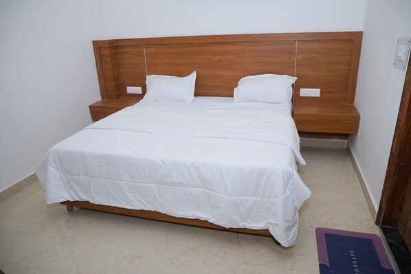 A single-bed room with a wooden headboard, white bedding, and a bedside table.