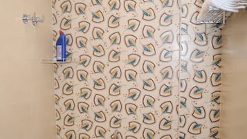 A bathroom with a shower curtain featuring a leaf pattern, a toilet, a sink, and a towel rack.