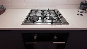 Une cuisine équipée d’une cuisinière à gaz, d’une hotte aspirante et d’un plan de travail.