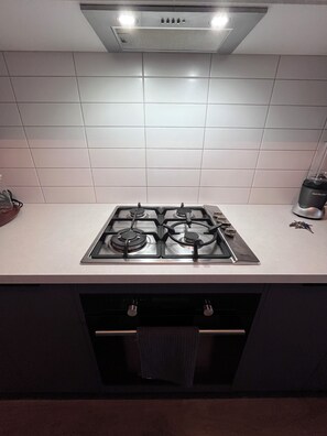 A kitchen with a gas stove, a range hood, and a countertop.