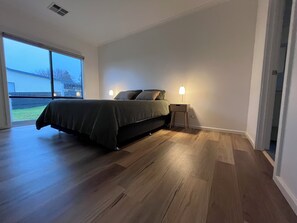 A bedroom with a bed, bedside tables, and a view through a large window.