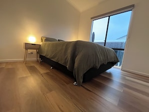 Una camera da letto con un letto, un comodino, una lampada e un'ampia finestra.
