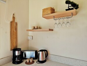 Eine Küchenzeile mit Toaster, Kaffeemaschine und Tassen auf der Arbeitsfläche.