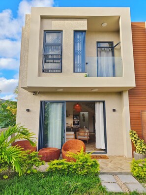 A modern two-story building with a balcony, a sliding glass door entrance, and a visible kitchen area. - Designer Luxury villa, 10 mins walk from beach (Grand Baie)