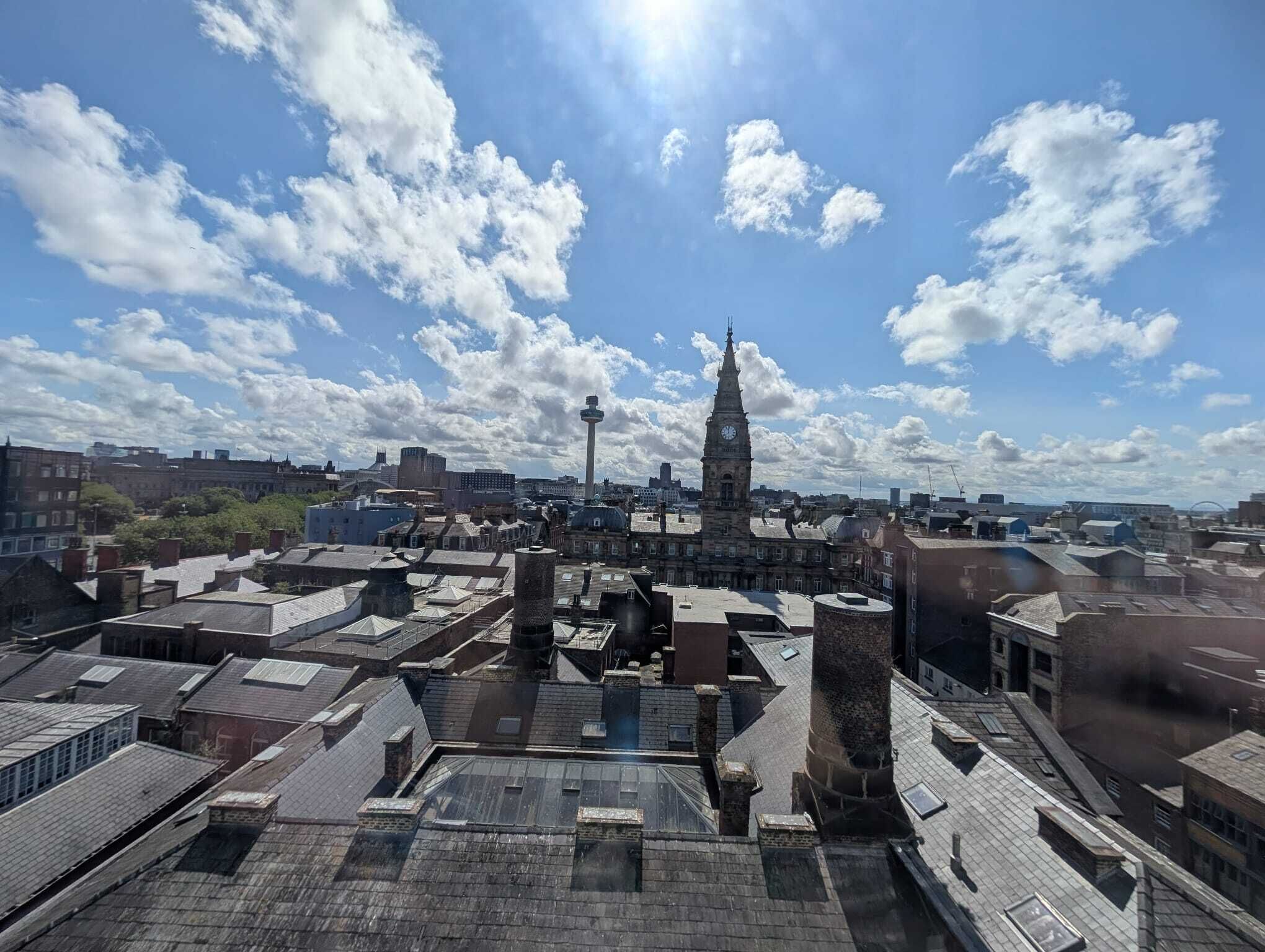 Un paisaje urbano con una imponente torre de reloj, una torre con mirador esférico y una mezcla de edificios antiguos y modernos.