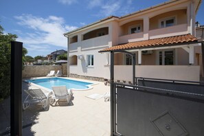 Un bâtiment à deux étages doté d’une piscine, d’un espace extérieur aménagé et d’une entrée sécurisée par un portail.
