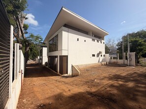 A modern two-story building with a flat roof and large windows. - Brisas Tranquilas #1 is a private 2-bedroom, 2-bathroom retreat with a fully equipped kitchen, washer and dryer, private pool, and parking. Enjoy a peaceful and comfortable stay with everything you need for a relaxing getaway. (Playas Del Coco)