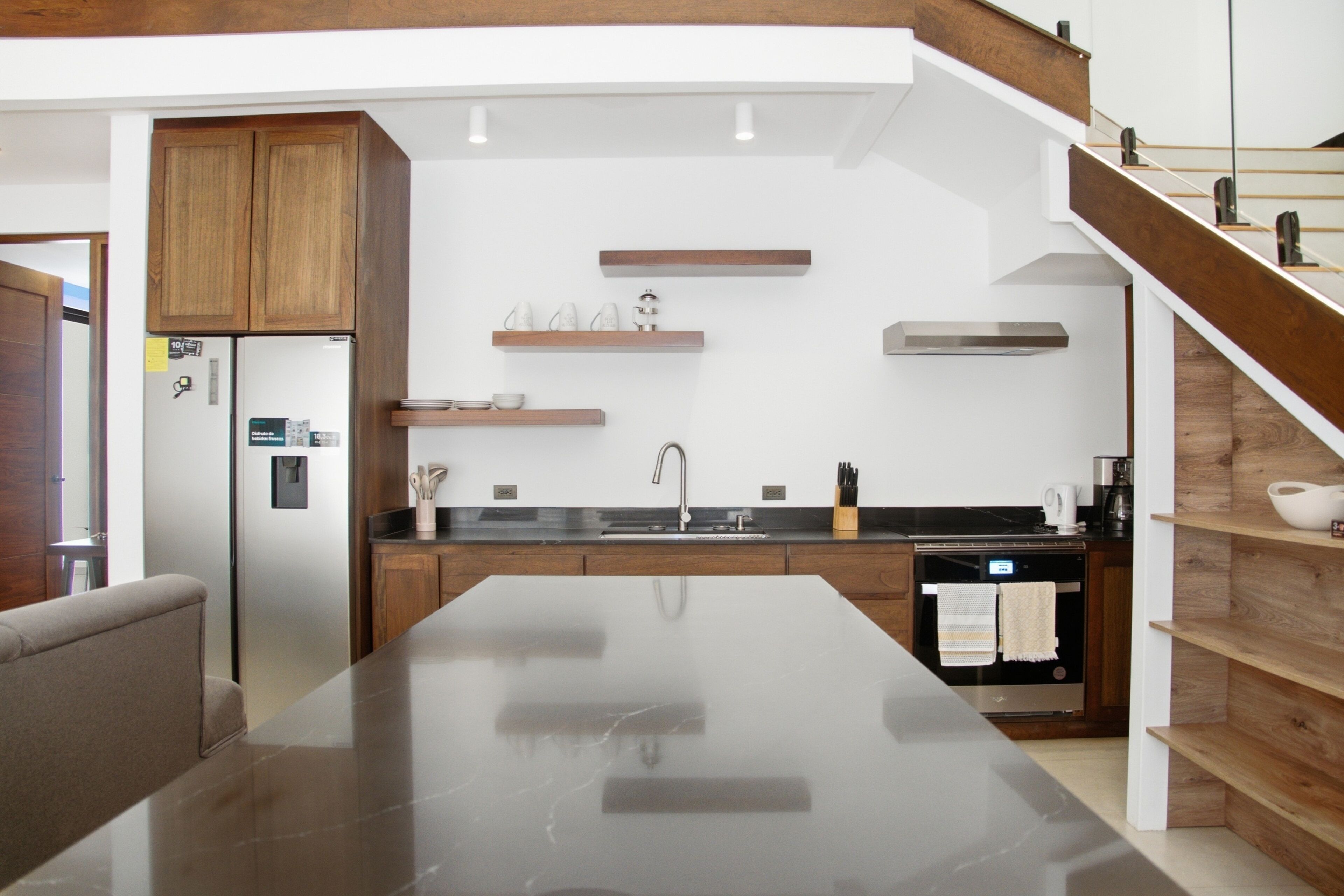 Een moderne keuken met een centraal eiland, houten kasten en inbouwplanken.