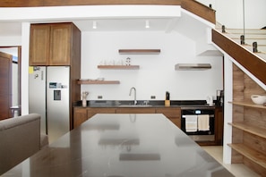 A modern kitchen with a central island, wooden cabinets, and built-in shelves. - Brisas Tranquilas #1 is a private 2-bedroom, 2-bathroom retreat with a fully equipped kitchen, washer and dryer, private pool, and parking. Enjoy a peaceful and comfortable stay with everything you need for a relaxing getaway. (Playas Del Coco)