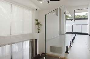 Un intérieur moderne avec une cloison en verre, une plante en pot et une vue sur l’extérieur.