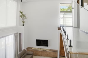 A modern living room with a sofa, a flat-screen TV, and a potted plant. - Brisas Tranquilas #1 is a private 2-bedroom, 2-bathroom retreat with a fully equipped kitchen, washer and dryer, private pool, and parking. Enjoy a peaceful and comfortable stay with everything you need for a relaxing getaway. (Playas Del Coco)