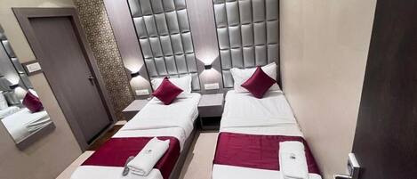 A hotel room with two beds, a large padded headboard, and a mirror above the beds.