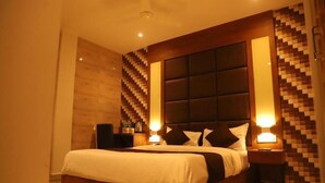 A hotel room with a large bed, wooden headboard, and a wall with a geometric pattern.