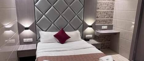Une chambre d’hôtel moderne avec un grand lit, des tables de chevet, une tête de lit et un ventilateur de plafond.