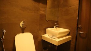A bathroom with a white sink, a mirror, and a shower head.