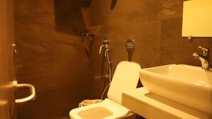 A bathroom with a toilet, a sink, and a shower area.