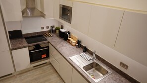 Uma cozinha moderna com forno embutido, micro-ondas e pia de aço inoxidável.