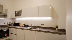 Eine moderne Küche mit weißen Schränken, einem Edelstahlbackofen, einer eingebauten Mikrowelle und einer Arbeitsplatte aus Granit.