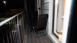 Ein Balkon mit Metallgeländer, einem Stuhl und einem Tisch.