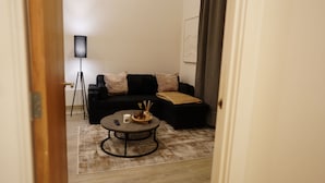Ein Wohnzimmer mit einer schwarzen Couch, einem Couchtisch und einer Stehlampe.