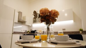 Une table à manger avec des assiettes, des verres et un vase de fleurs dans une cuisine moderne.