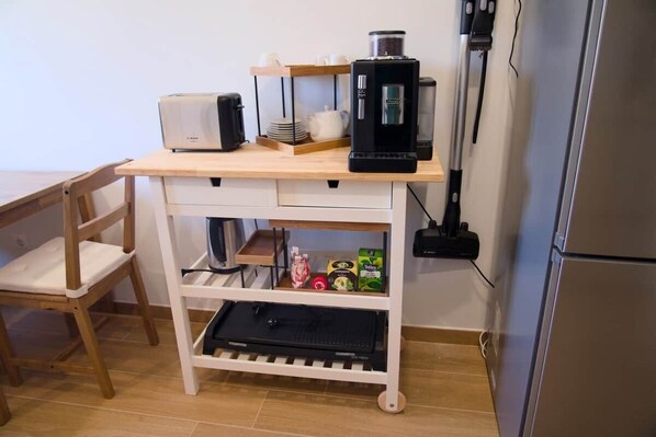 A kitchenette with a coffee maker, toaster, and storage shelves.