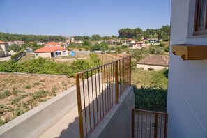 Un barrio residencial con casas, cielo despejado y un balcón con baranda de metal.