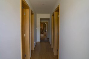 A hallway with wooden doors leading to a room.