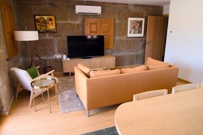 Una sala de estar con un sofá, una televisión, una lámpara y una mesa de comedor.