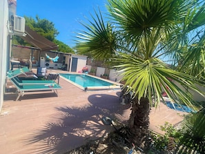 A swimming pool with lounge chairs, a palm tree, and a covered patio area. - Villa Oasis • Private Pool • 5 minutes from the ocean • Frontignan (Frontignan)