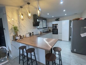 A modern kitchen with a marble backsplash, stainless steel appliances, and pendant lighting. - Villa Oasis • Private Pool • 5 minutes from the ocean • Frontignan (Frontignan)