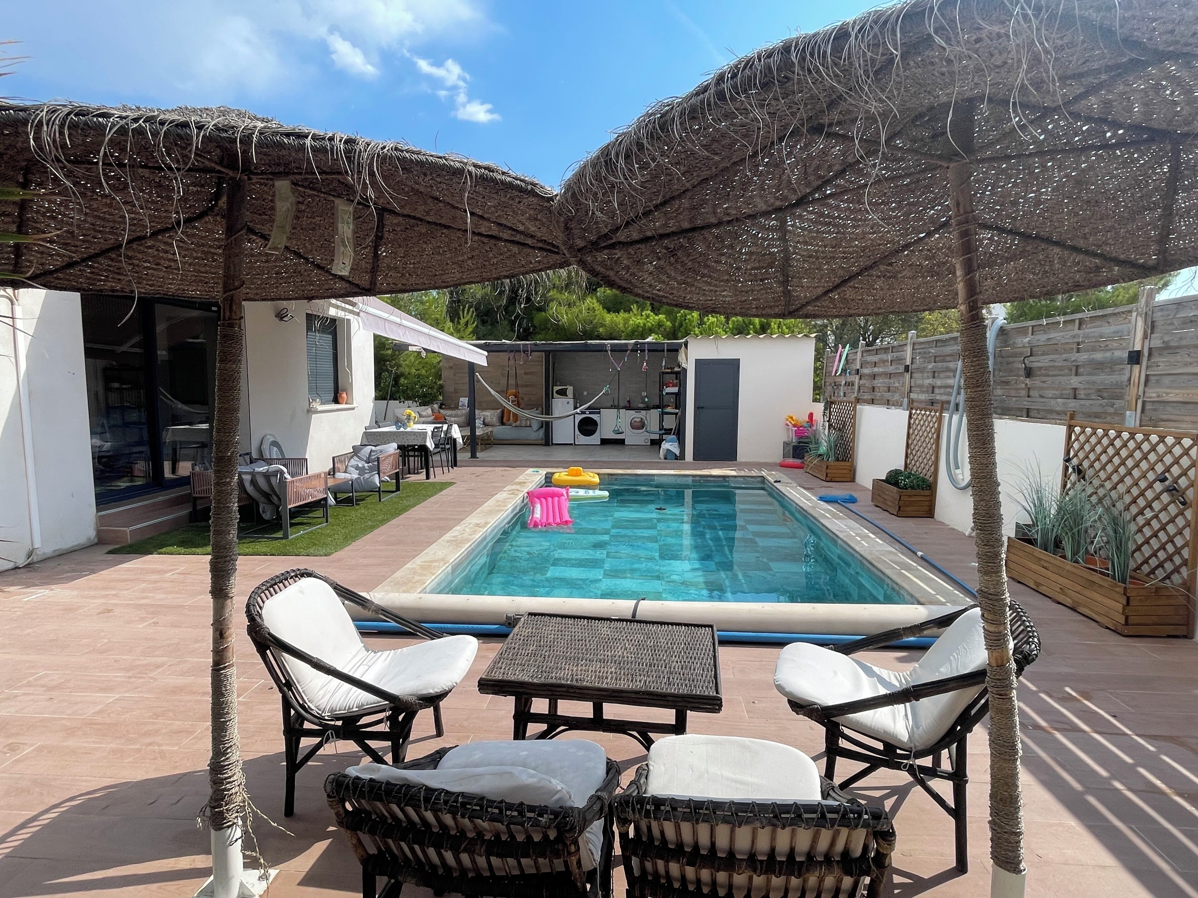 Un jardin avec une piscine, du mobilier d’extérieur et un patio couvert.