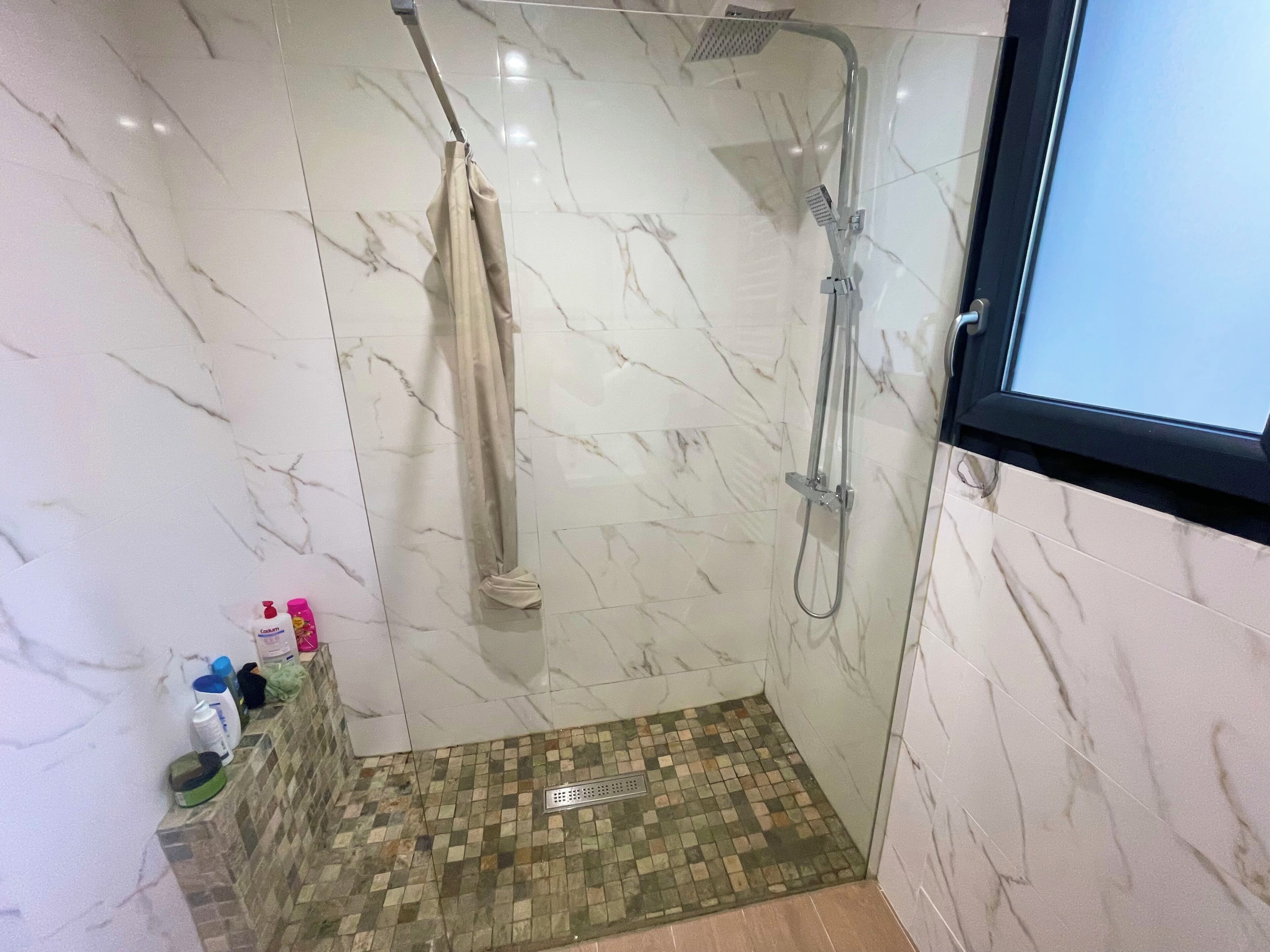 A shower area with a glass door, a showerhead, and a curtain.
