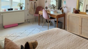 A bedroom with a bed, a desk, a chair, a radiator, a window, and a wall clock.