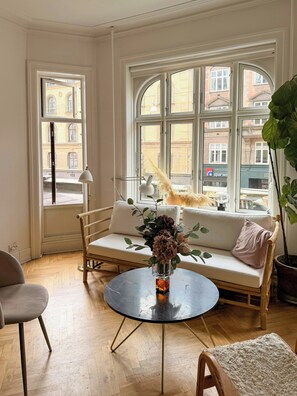 A room with a sofa, a round table, and a chair. There are windows with a view of buildings outside. - Historic flat from the 1850s in Frederiksberg (Frederiksberg)