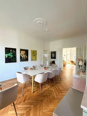 A spacious dining area with a large table and chairs, surrounded by white walls and wooden flooring. - Historic flat from the 1850s in Frederiksberg (Frederiksberg)