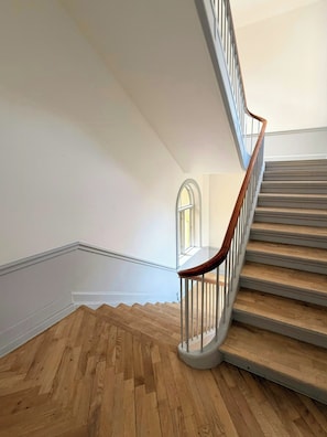 A wooden staircase with a wooden handrail and white balusters, leading to a landing with a white wall and a window. - Historic flat from the 1850s in Frederiksberg (Frederiksberg)