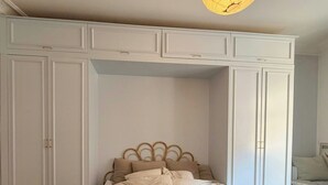 Een slaapkamer met een bed, een hanglamp en inbouw-kasten.