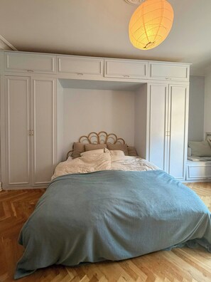 A bedroom with a bed, a hanging light fixture, and built-in wardrobes. - Historic flat from the 1850s in Frederiksberg (Frederiksberg)