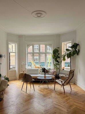 A room with a herringbone floor, a white sofa, a round table, and a large plant. - Historic flat from the 1850s in Frederiksberg (Frederiksberg)