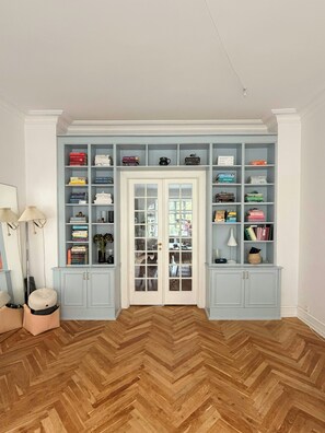 A room with a herringbone wood floor, a white door with glass panels, and a light blue built-in bookshelf with various items. - Historic flat from the 1850s in Frederiksberg (Frederiksberg)