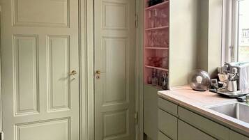 A kitchen with two double doors, a countertop with various kitchen items, and a window.