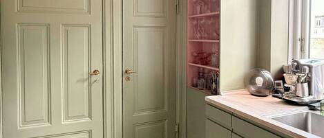 A kitchen with two double doors, a countertop with various kitchen items, and a window.