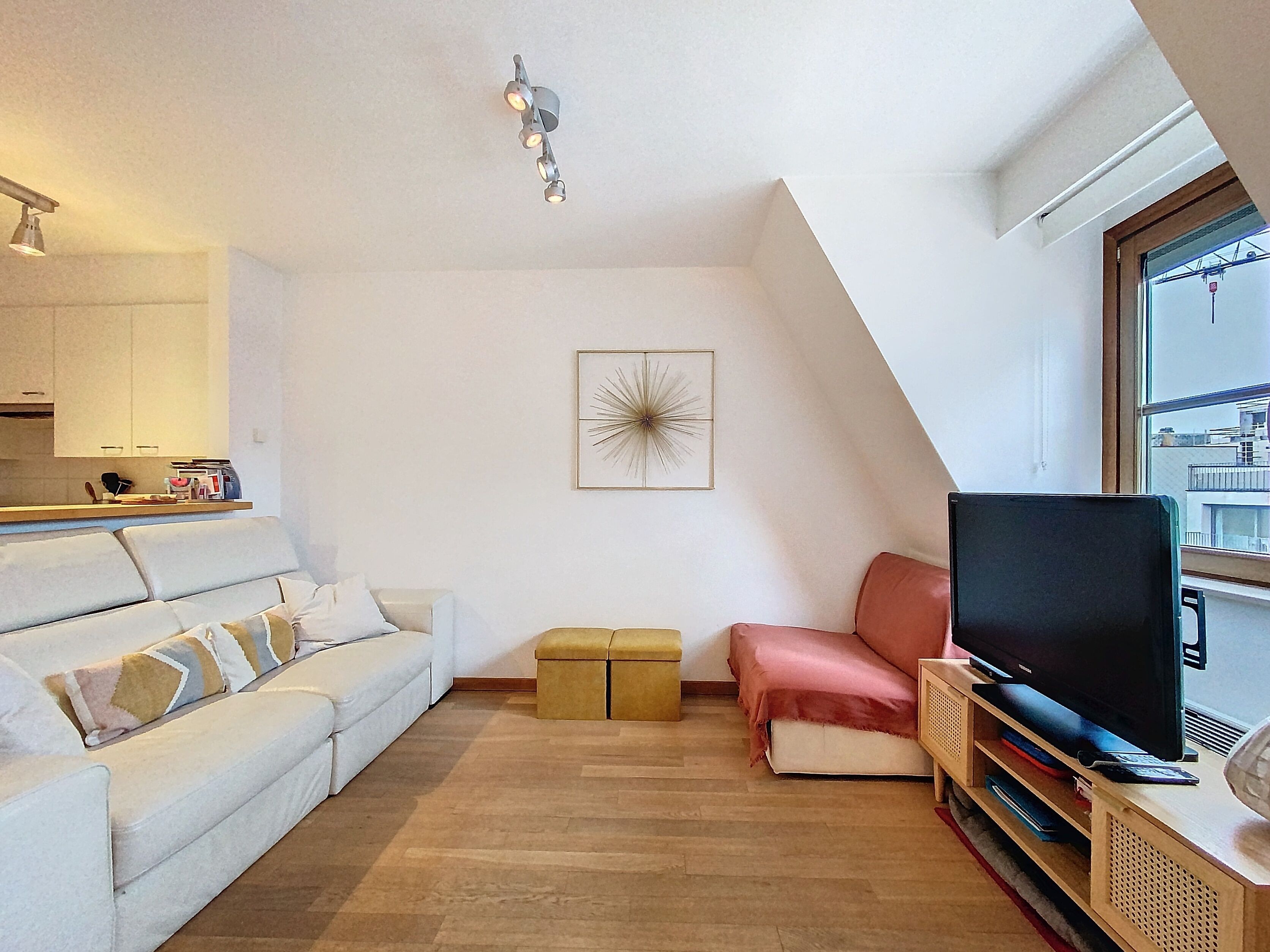 A modern living room with a sofa, a small table, a television, and a picture on the wall.