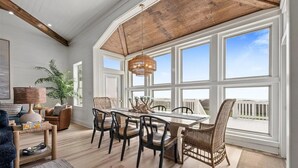 Un comedor con mesa y sillas de madera, ventanas amplias y vistas al exterior.