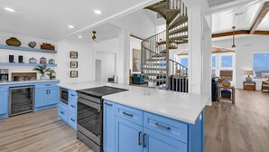 Una cocina moderna con armarios azules, una isla central y una escalera que sube a un nivel superior.